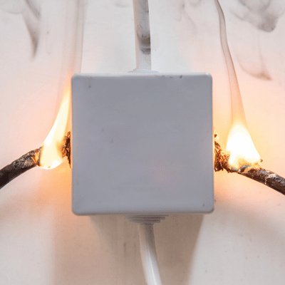 Burning Smell? Call An Emergency Electrician Now 1 Wall outlet smokes and sparks from overheating wires as emergency electrician responds to stop fire.