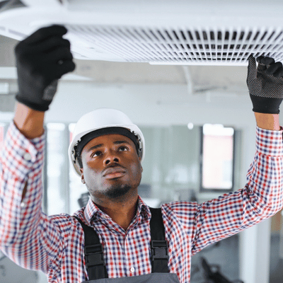 Commercial Electrical Repair For Offices And Retail Spaces 1 Worker removes ceiling vent cover during commercial electrical repair to access wiring and equipment.